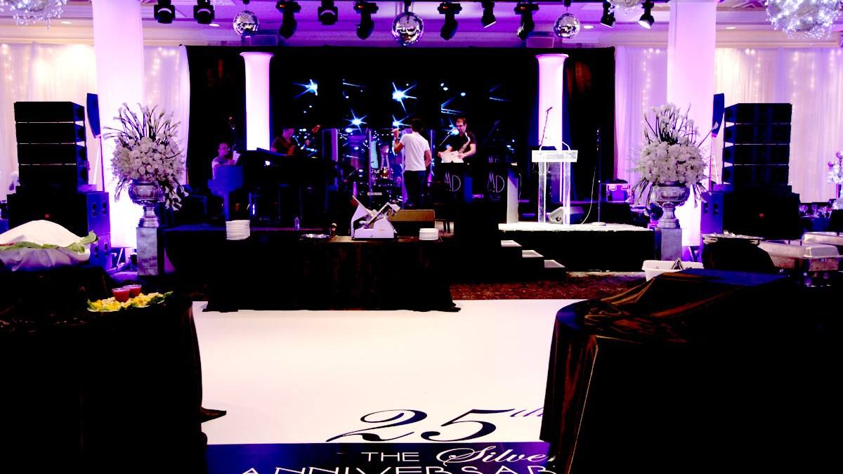 Corporate gala room set for dinner with a lit stage and a branded floor panel