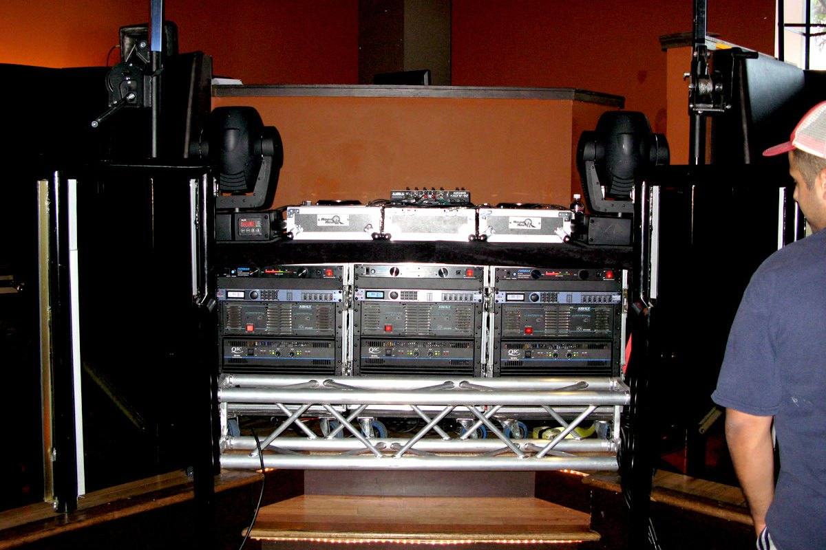 Amplifier racks and flight cases stacked under the rig during load-in